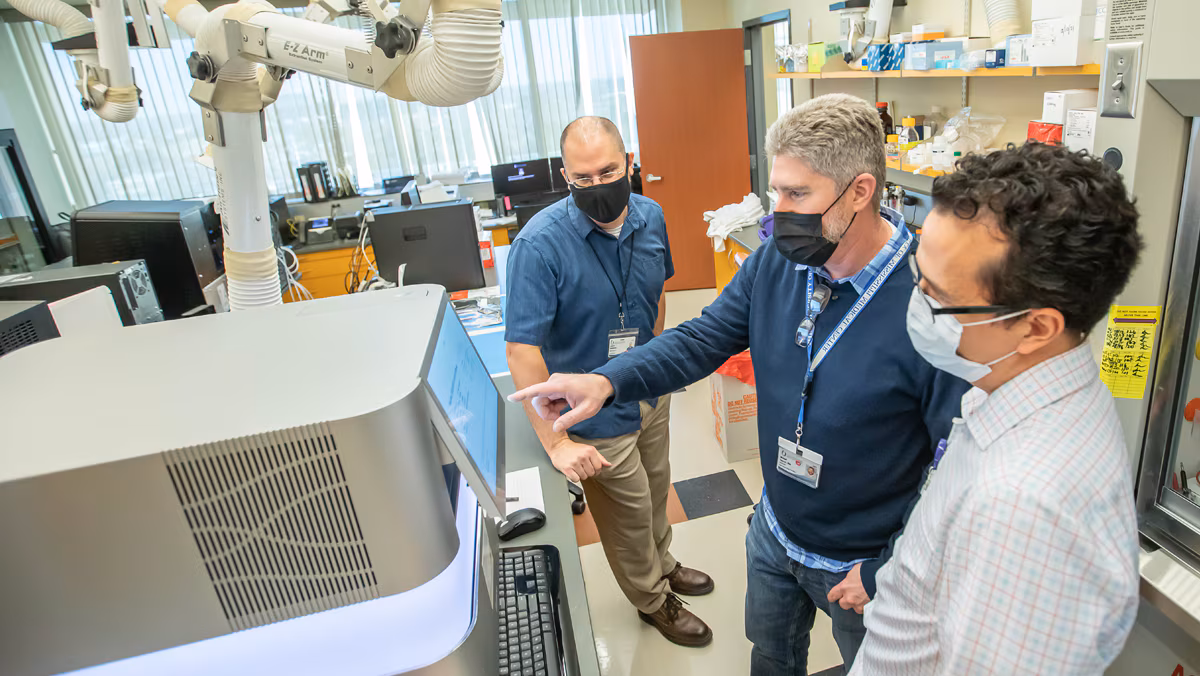 3 men in talking in a lab