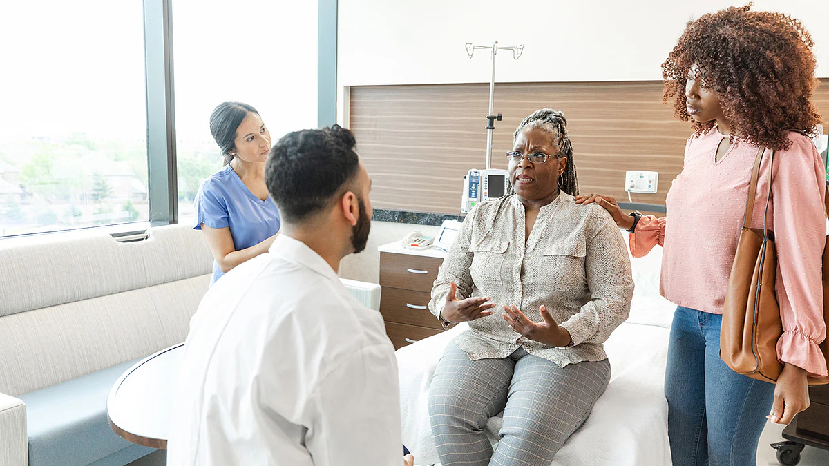 Serious woman and daughter talk to male doctor Woman talking with doctor with family present