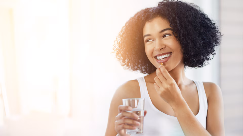 — title missing — Young woman smiles taking a vitamin.