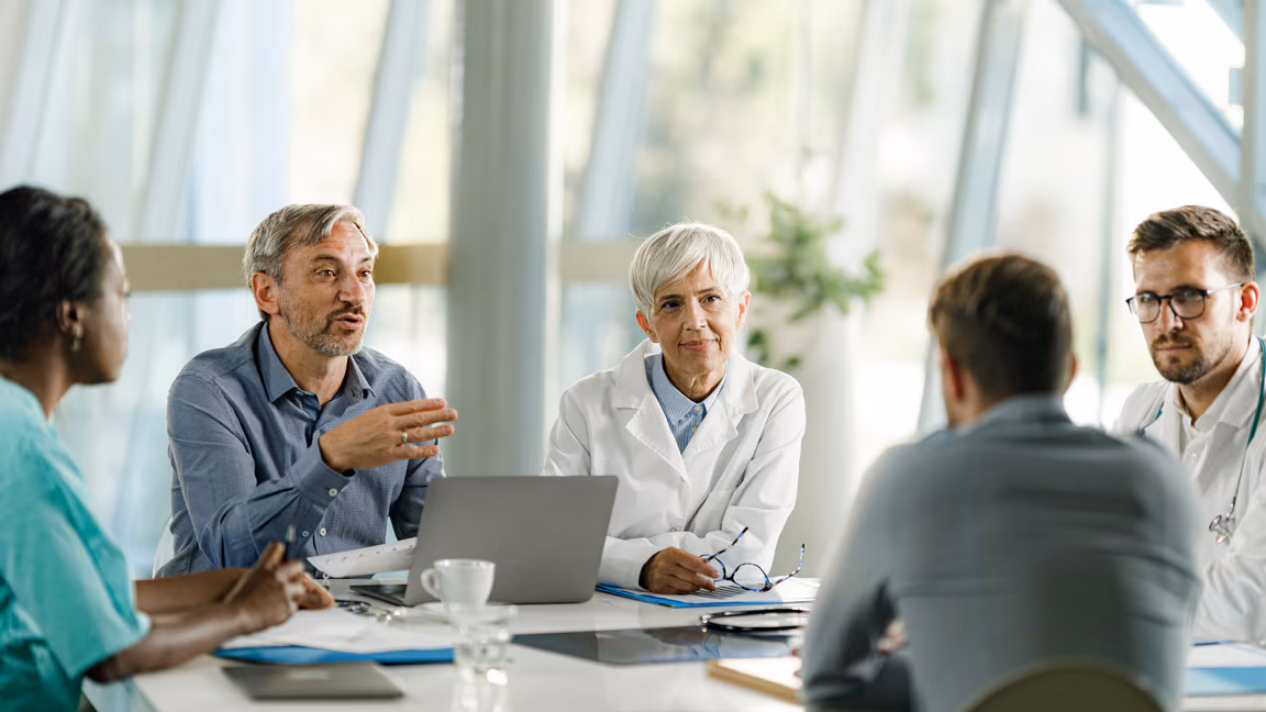 How to Use the mPINC Steps A team of doctors and hospital administrators have a meeting in the hospital.