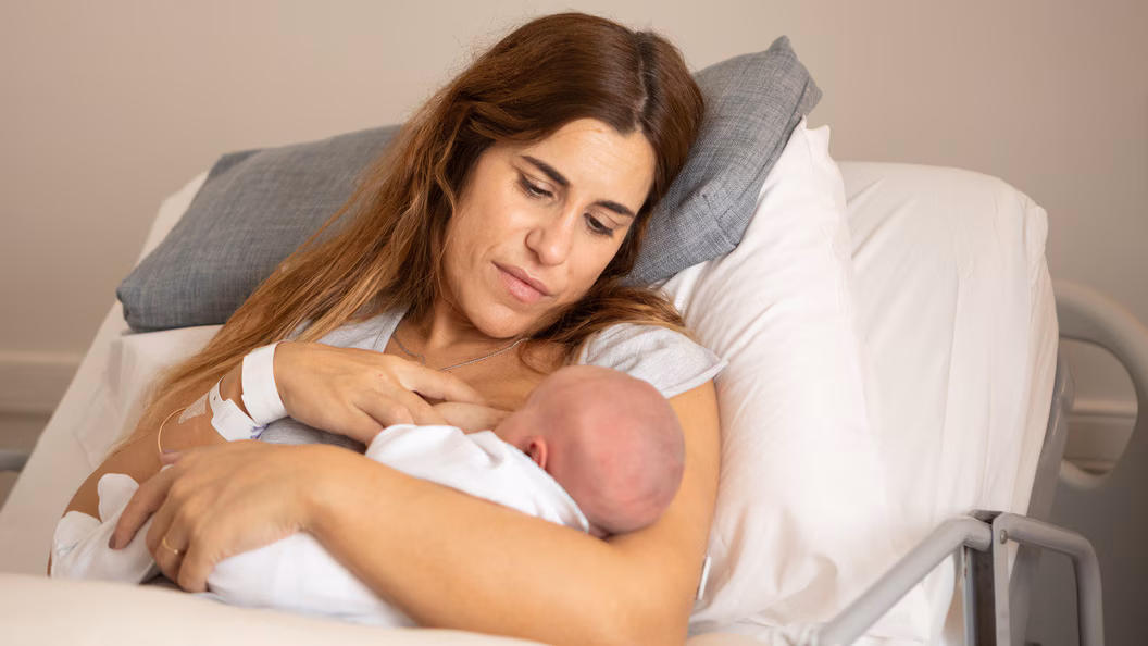 mPINC FAQ breastfeeding mom A newborn baby with their mom in a hospital bed.
