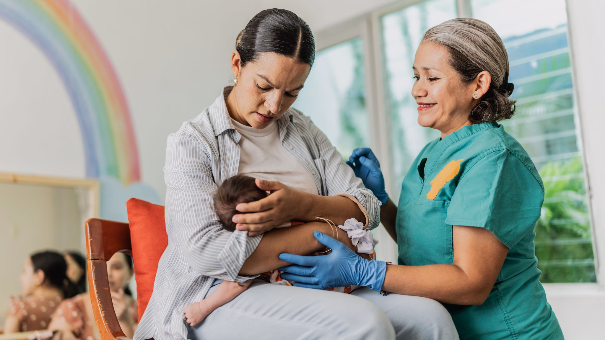 Mom getting breastfeeding support A health care provider helps a new mom with breastfeeding her baby.