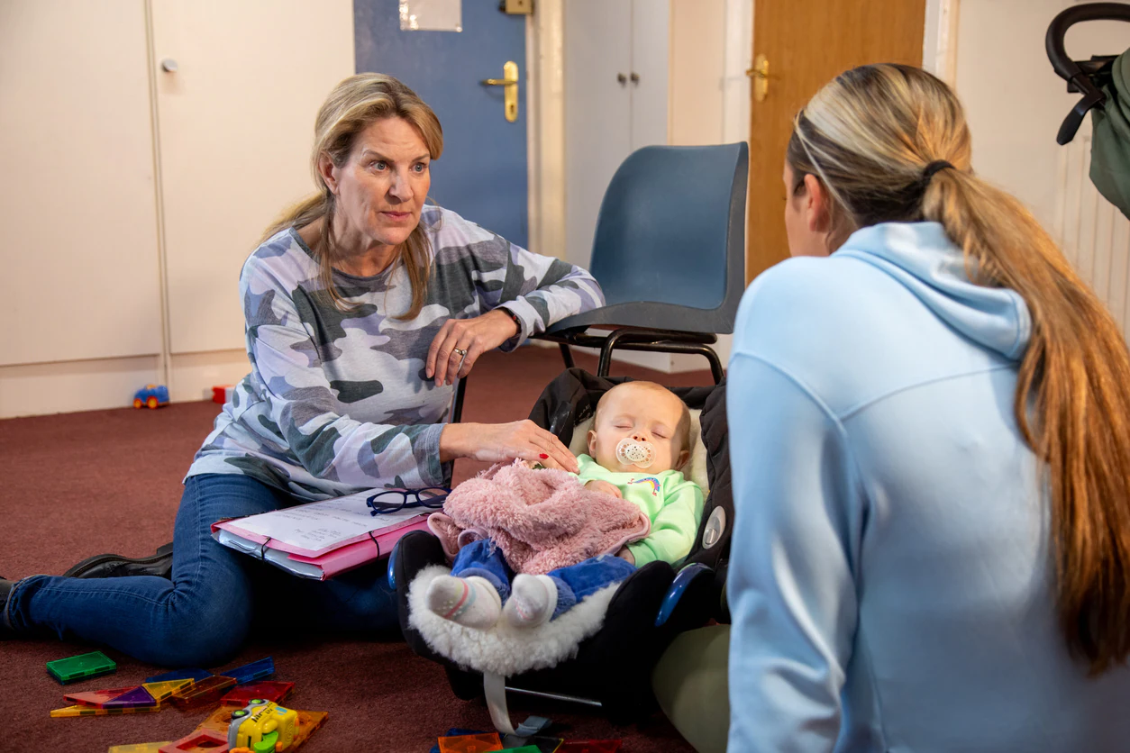 Child Care Worker with Young Adult A mother and baby child having a meeting with a childcare worker.