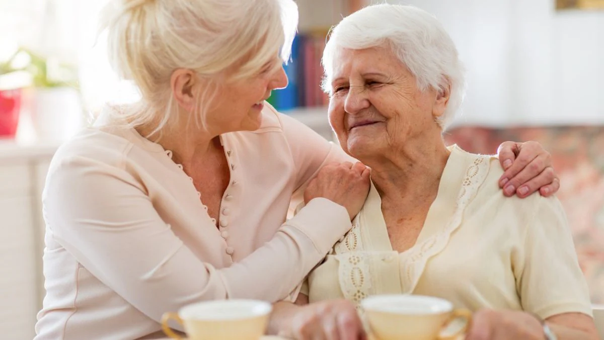 Caregiver and older adult having tea Older woman caregiver with white hair having tea with a much older woman with white hair.