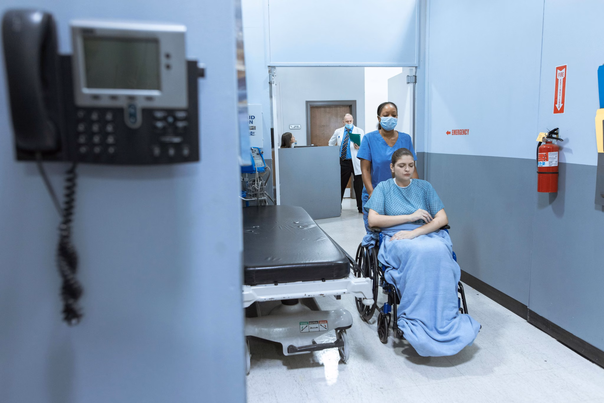 healthcare staff & patient Healthcare personnel pushing patient in wheelchair.