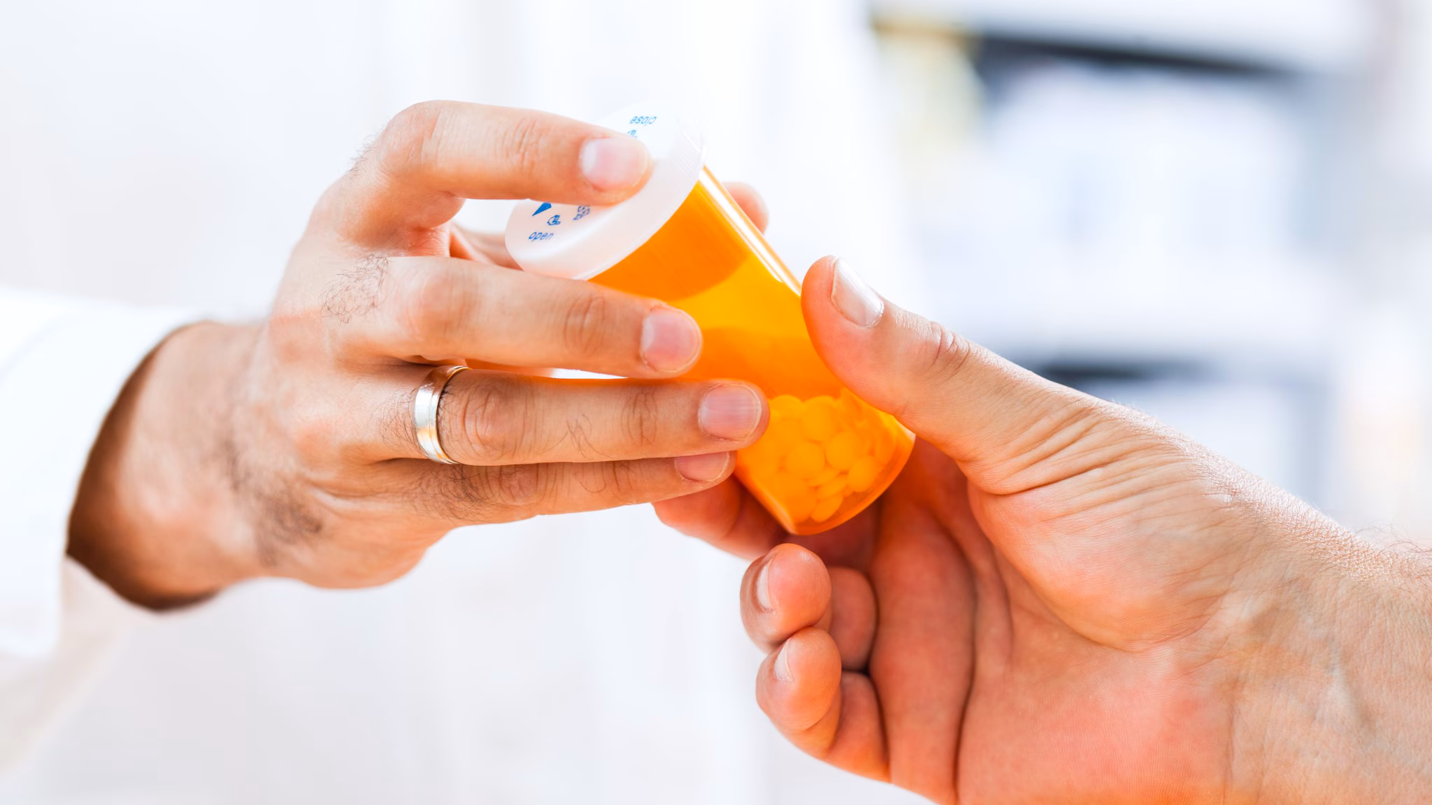 Doctor handing a patient a bottle of pills.