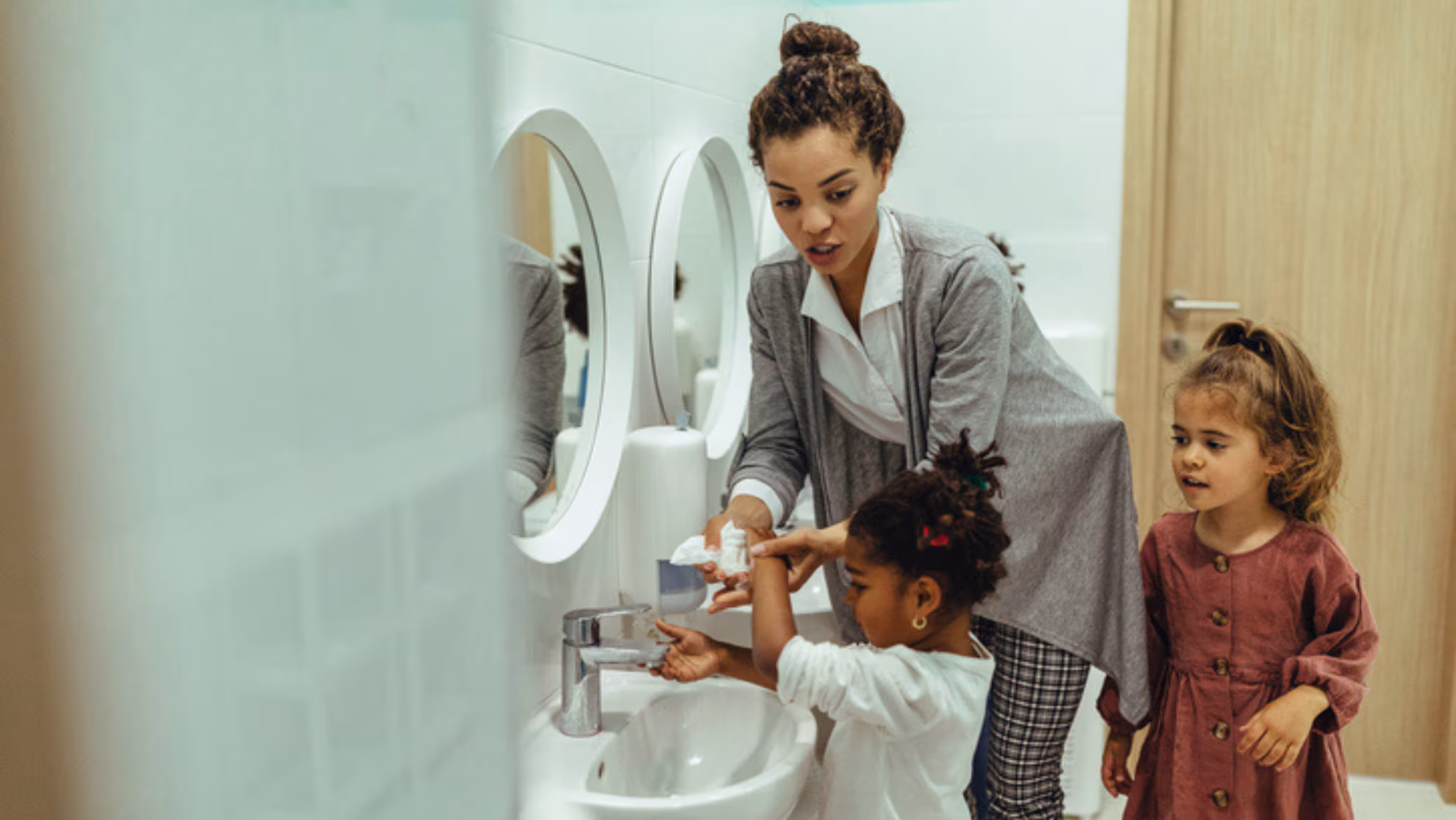 teacher helping child wash their hands teacher helping child wash their hands