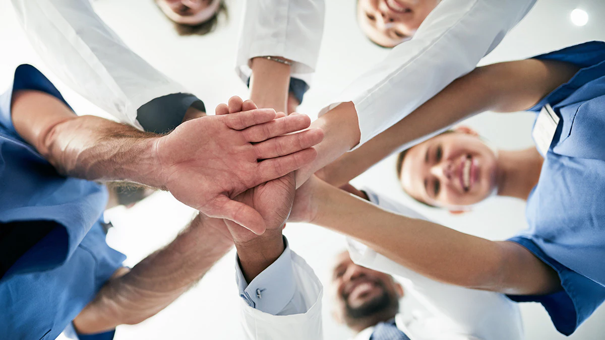 Stroke systems of care A group of medical professionals standing in a circle and joining their hands together in the middle
