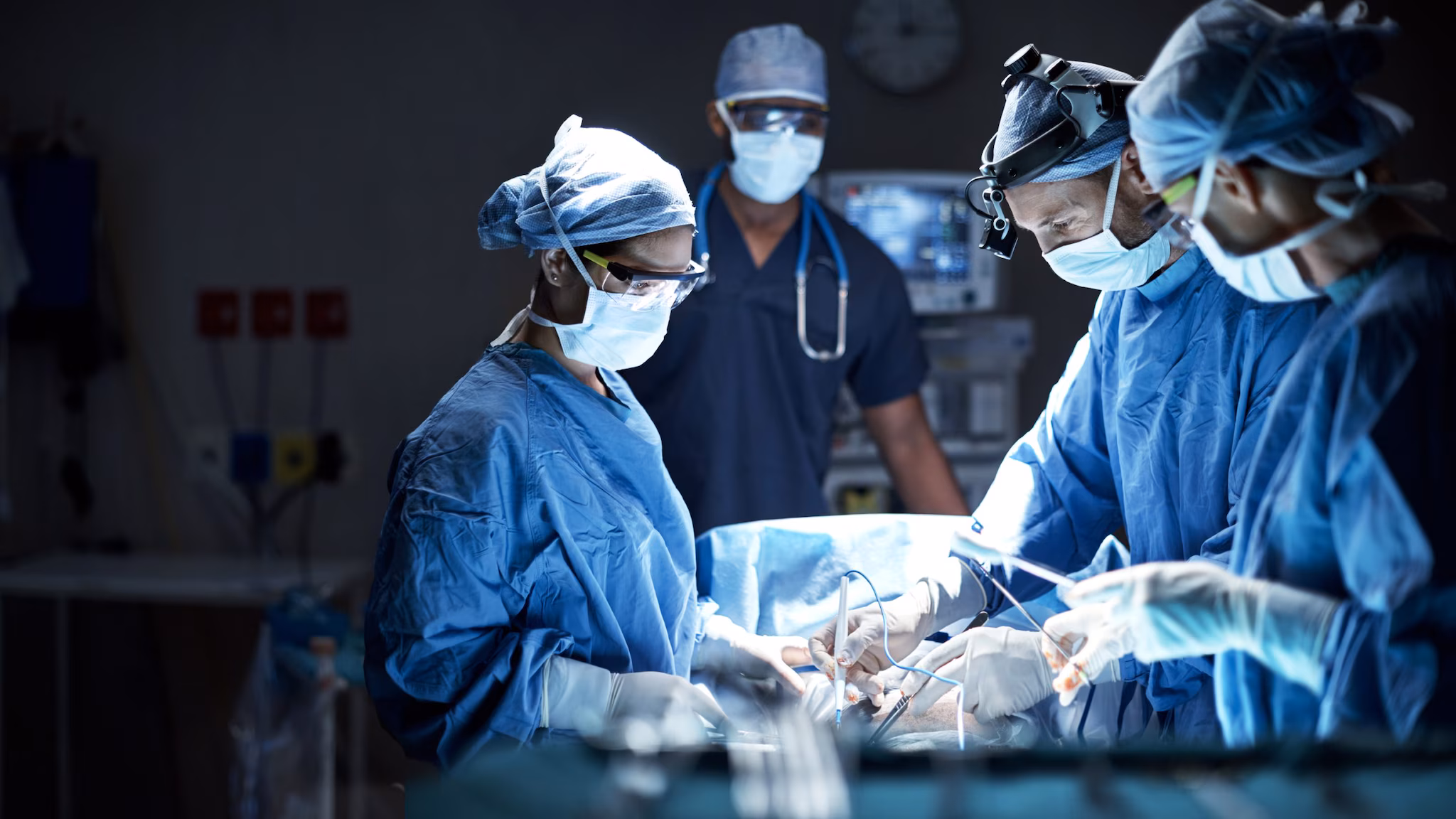 Several healthcare personnel operate on a patient.