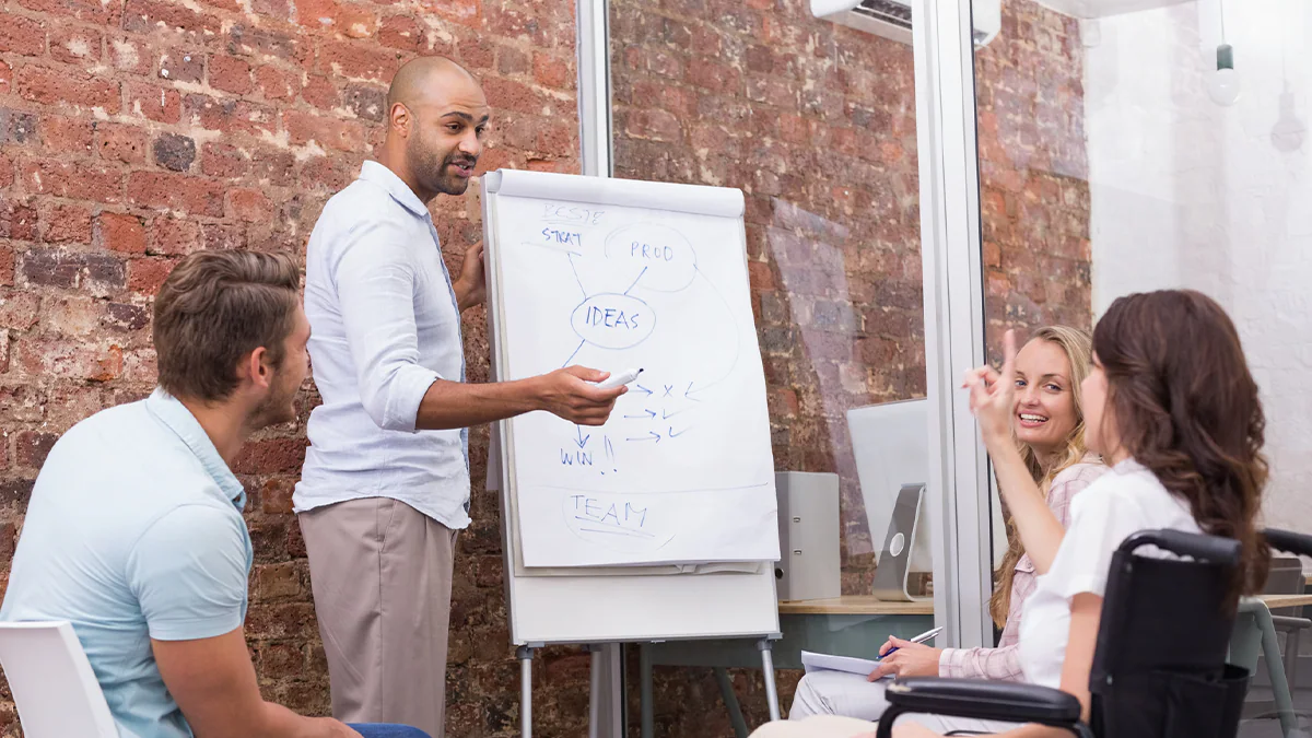 People at business meeting looking at whiteboard Businessman making a presentation to his fellow coworkers