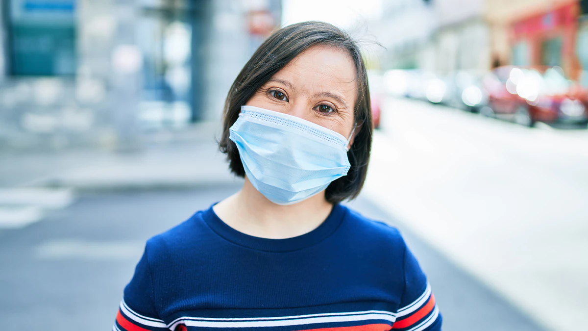 Woman with a disability wearing a mask in the street Woman with Down Syndrome wearing a mask.