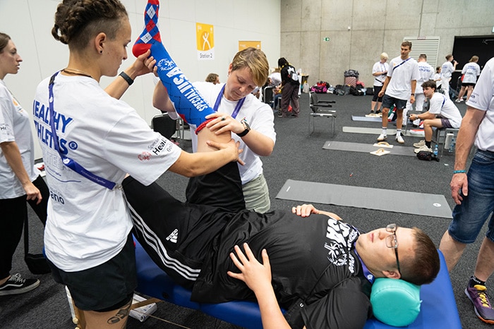 Trainers helping a Paralympic athlete stretch Trainers helping a Paralympics athlete stretch