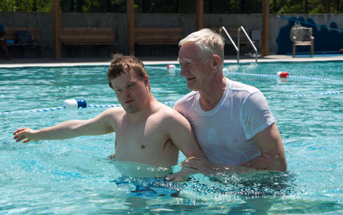 boy-man-pool-500px.jpg A man helps a boy with Down Syndrome in a pool.