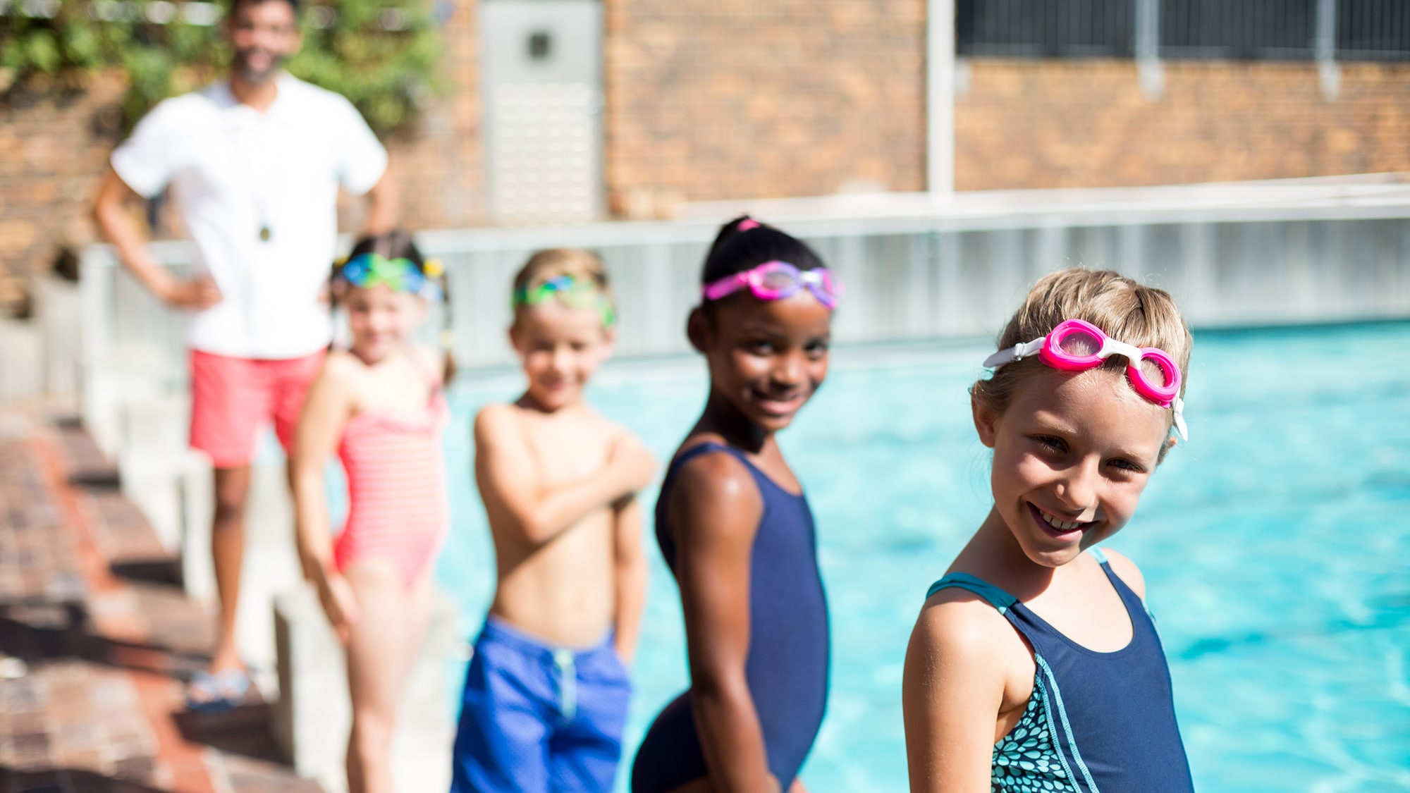 Kids at swim practice Children at an outdoor swimming lesson with adult swim instructor.