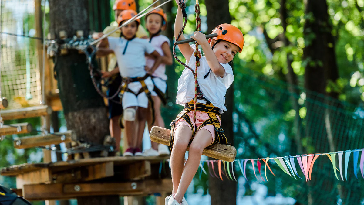 Youth on zipline in wooded area under sunny sky Youth on zipline in wooded area under sunny sky