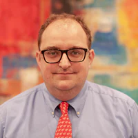 Jordon-Hillhouse White male with glasses and shirt and tie smiling