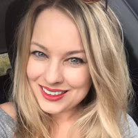 Melanie-Perdue White woman with light hair and gray shirt smiling