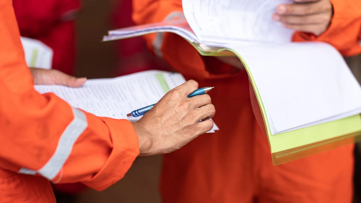 EH response and recovery publications People in orange safety suits looking at documents and clipboards