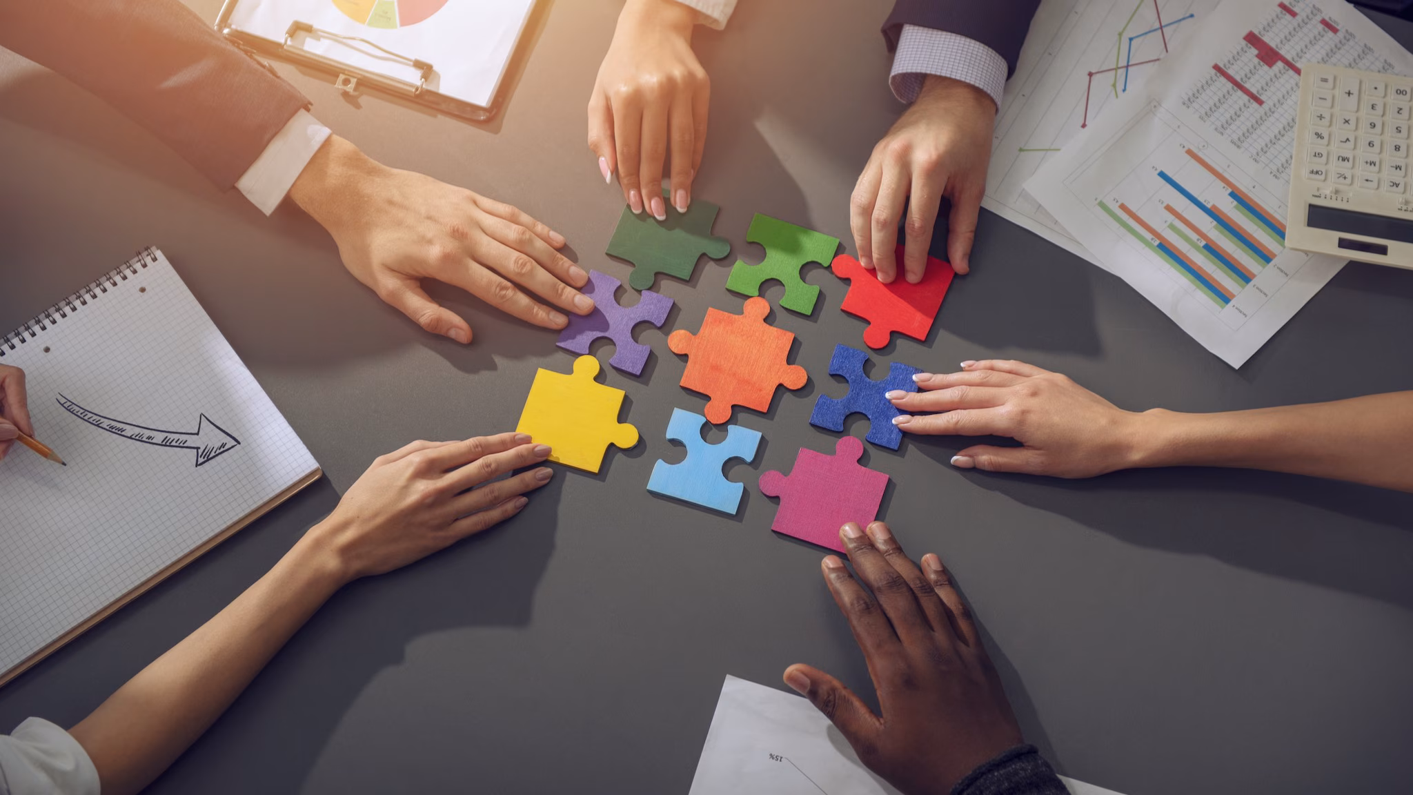Table top of hands holding colorful puzzle pieces
