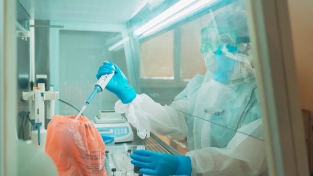 Lab-4 core list-second Person in PPE in a lab holding lab equipment.