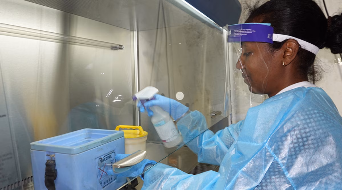 Ethiopia_MainImage Woman lab worker dressed in personal protective equipment sprays a container in a laboratory setting.