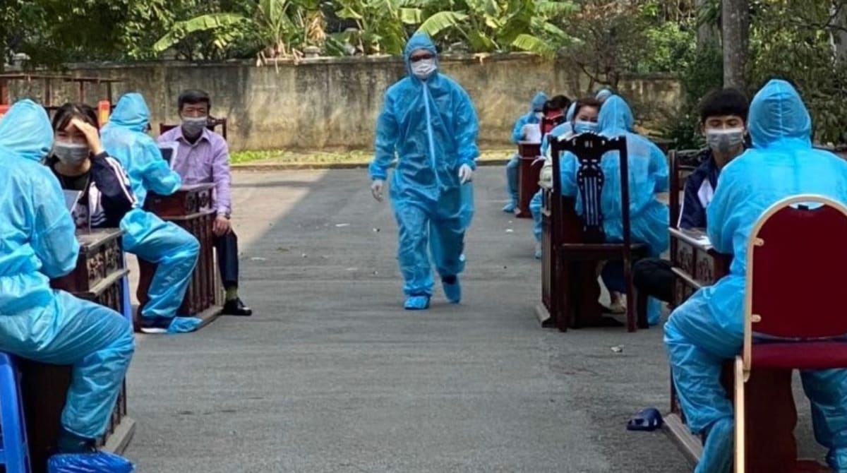 FETP_Fellows_Vietnam Worker walks outside an outside clinic dressed in blue PPE.