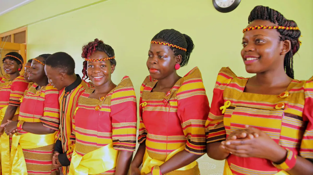 Uganda Main Image A group of smiling adolescents in gomesi attire.