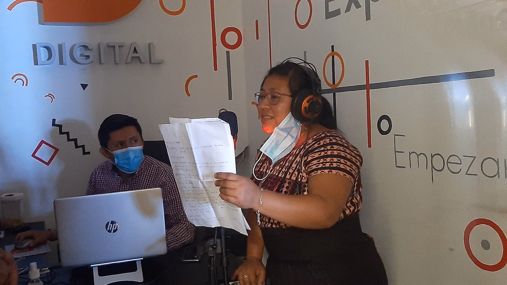 -- title missing -- A woman is seen reading from a paper and speaking into a microphone to record a segment that will air on a local radio station.