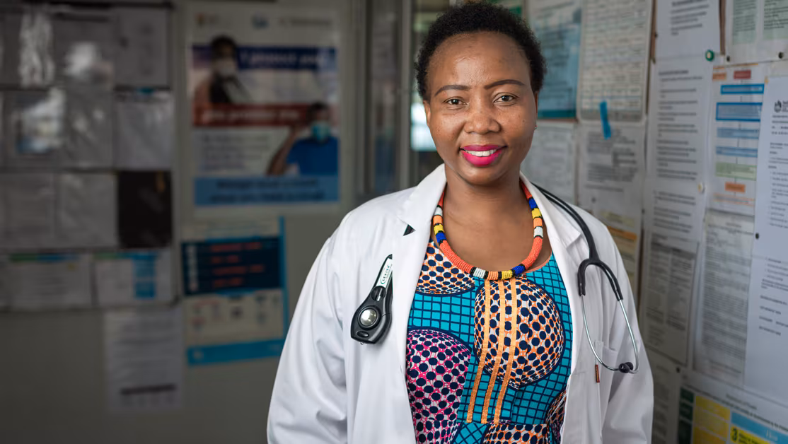 A woman in a white coat and multicolored dress.