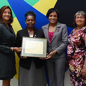 2024-06_SS_StCLL_Award2 Four women stand in front of a colorful background, holding a certificate.