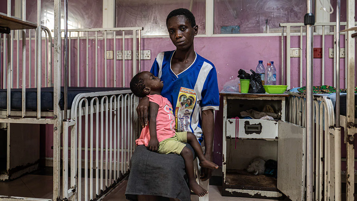 In Nigeria, this mother cradles her young daughter who is being treated for a severe measles infection. A mother cradles her daughter in a clinic.
