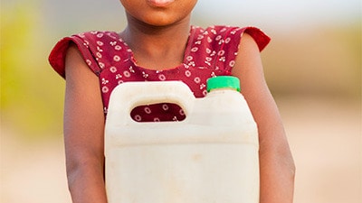 girl holding jug resized Young girl holding a plastic jug of water outside.