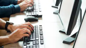 GrantSolutions Training Monitors and keyboards side by side with hands typing on the keyboards.