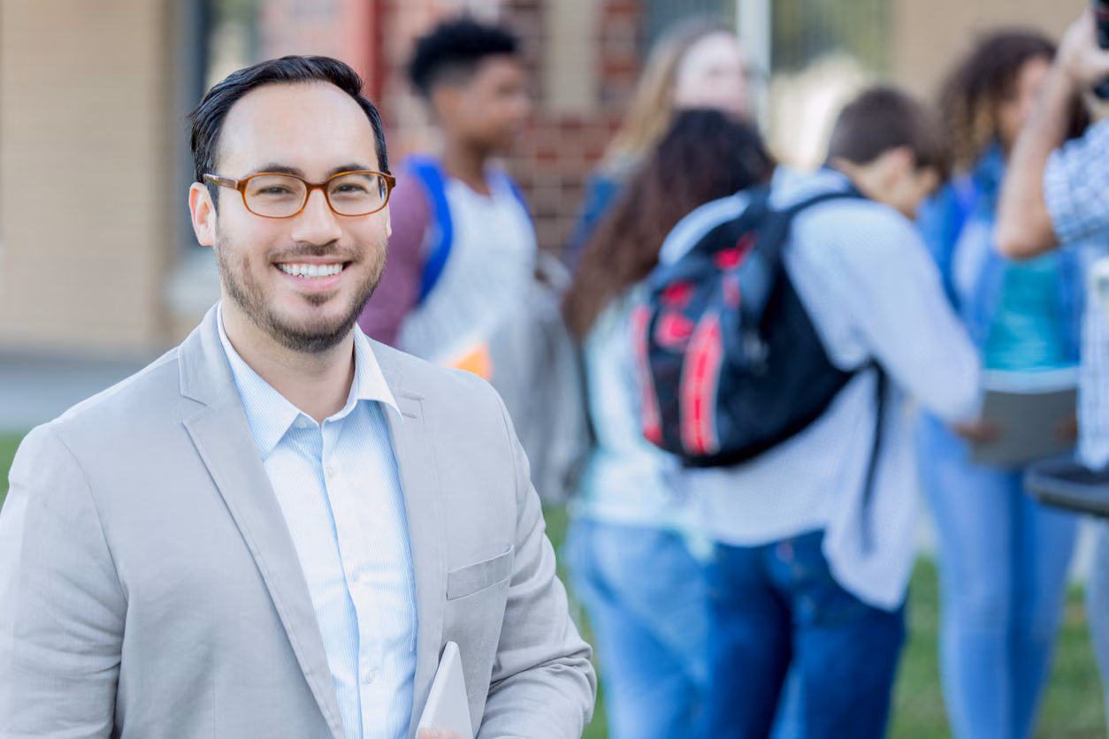istockphoto-1034421614-1024x1024 Confident teacher standing outside of school.