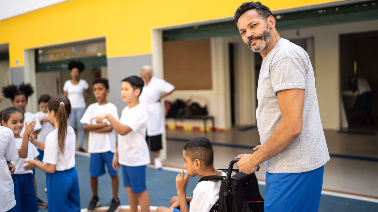 Portrait of a physical education teacher helping student with disabily at school teacher helping a student in a wheelchair