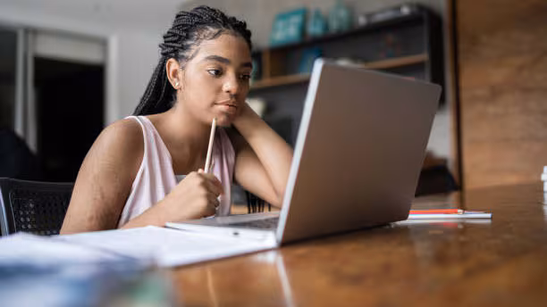 Journal Article A student reading information on a laptop at their desk.