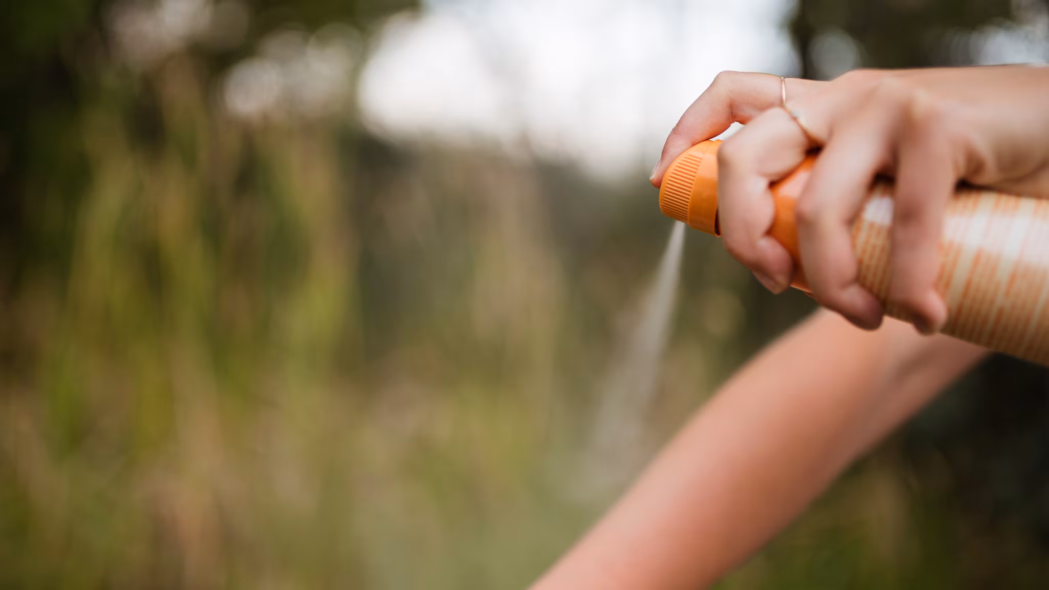 Person applying insect repellent to their arm.