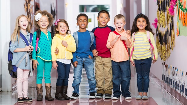 Young kids in a school hallway A group of 7 children standing in a school hallway, laughing and smiling at the camera. The boys and girls are 4 to 6 years.