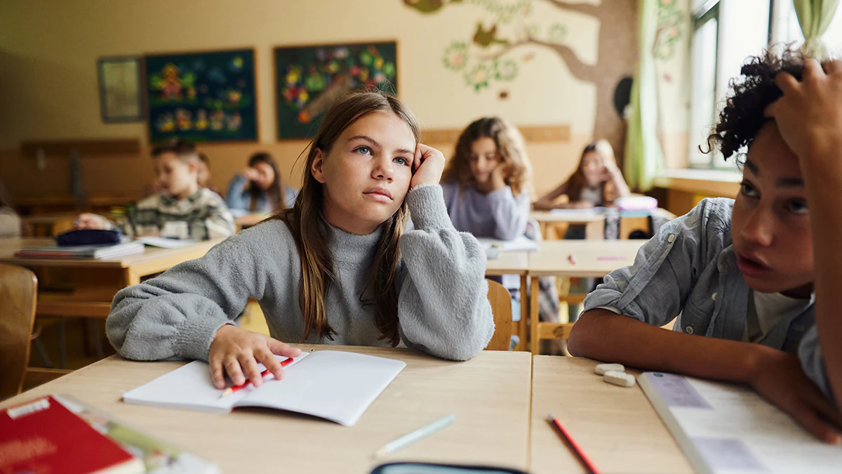 ME/CFS in Children Tired schoolgirl attending a class with her classmates at elementary school.