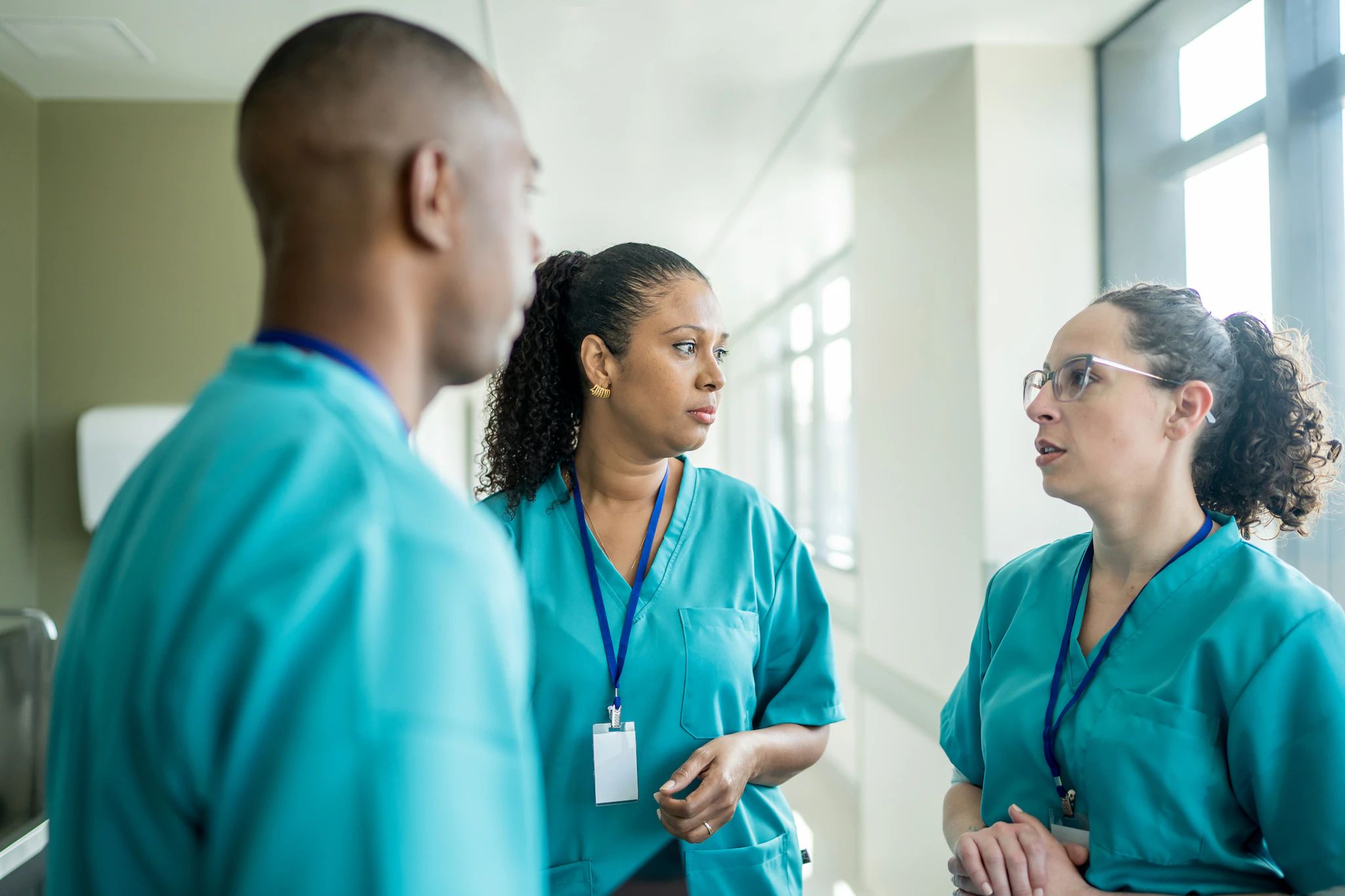Three health care providers discussing clinical interventions in a hospital setting Three health care providers discussing clinical interventions in a hospital setting