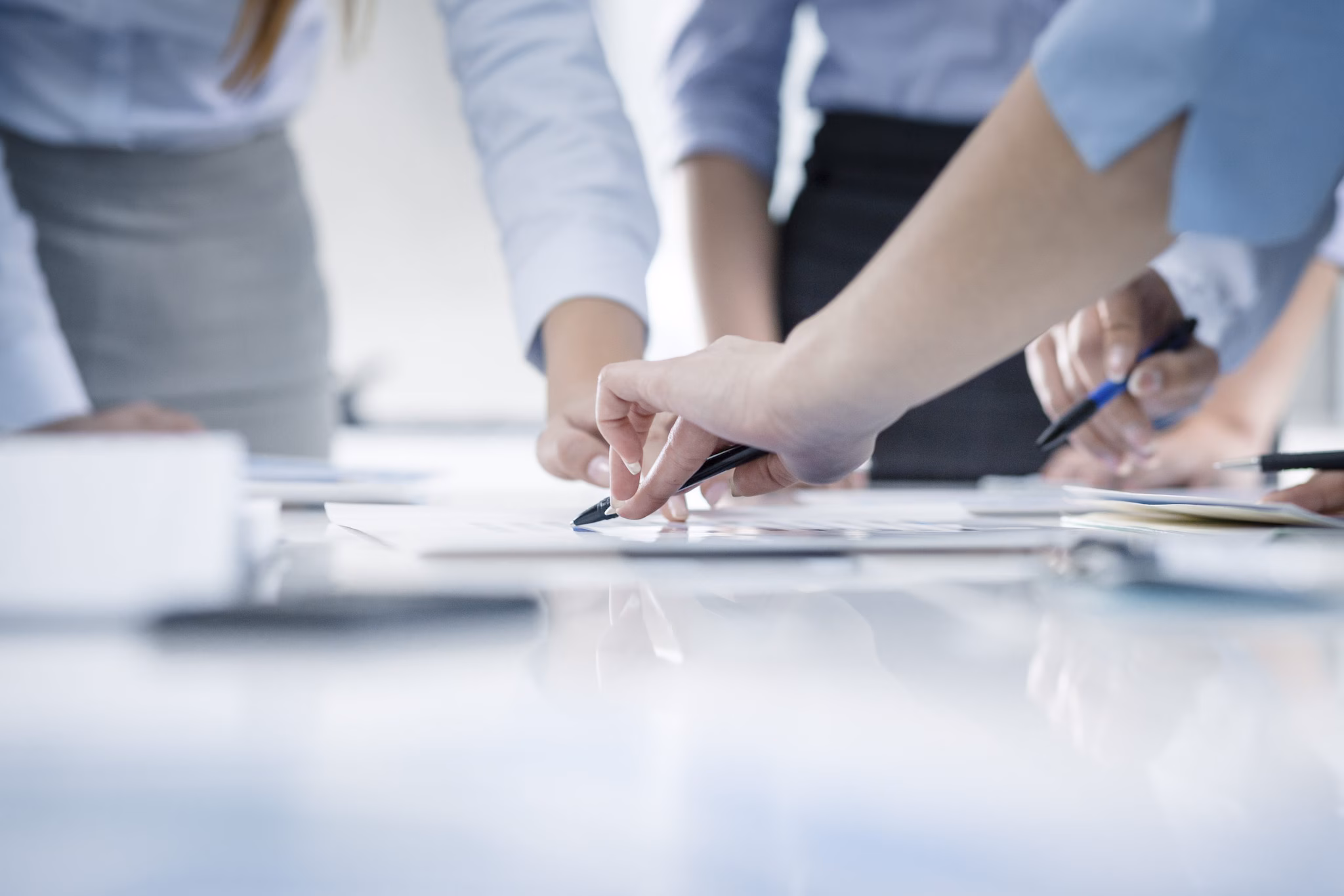 — title missing — Group of people gathered around documents on a table with only their hands visible.