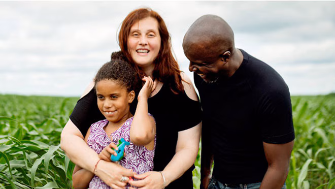A happy family standing in front of a field A happy family living with disability