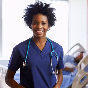Nurse standing in patient room with patient in the background.