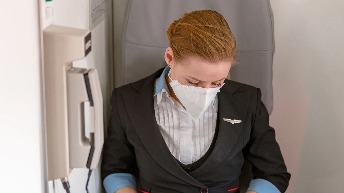1364780446 Female aircrew member seated aboard a commercial aircraft.
