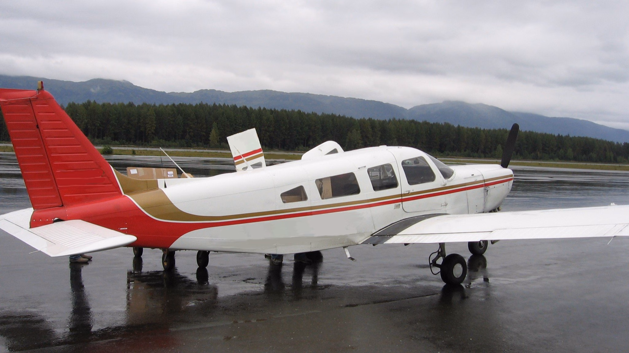 Alaska Aviation Thumbnail Small commuter plane with red stripe down the side on the runway under cloudy skies