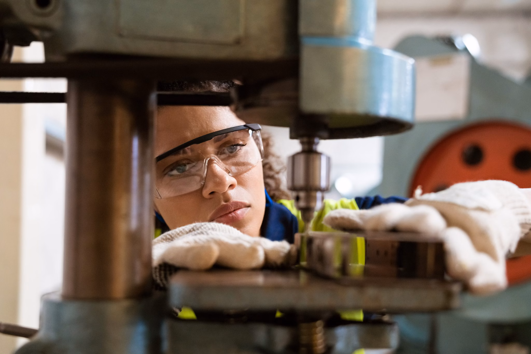 DD October 2024 Close up of a young female manufacturing worker wearing safety glasses and gloves using a machine.