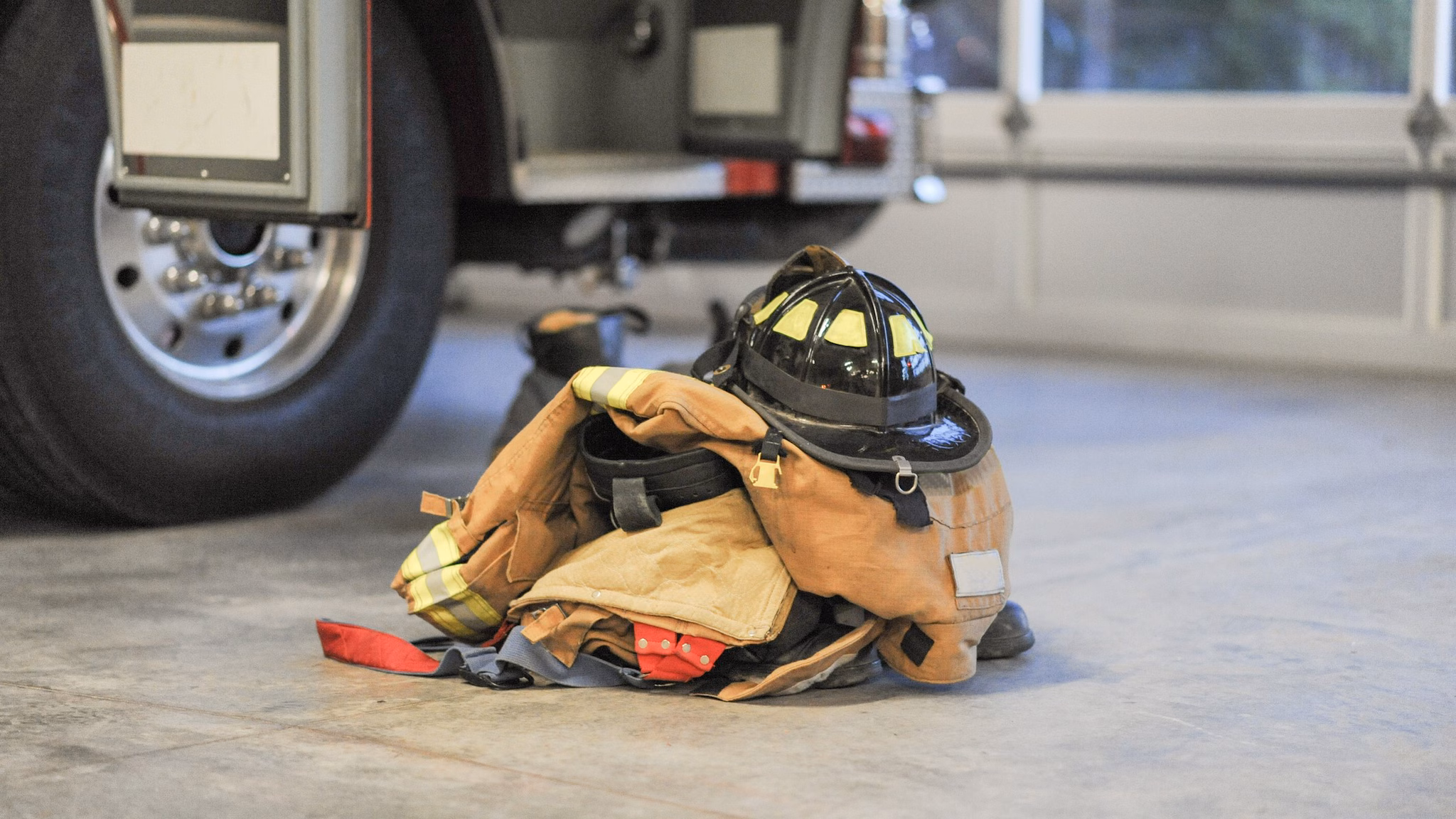 FFFIPP_Fatalities_SeriousInjuries_Thumbnail A stack of firefighter gear is next to a firetruck.