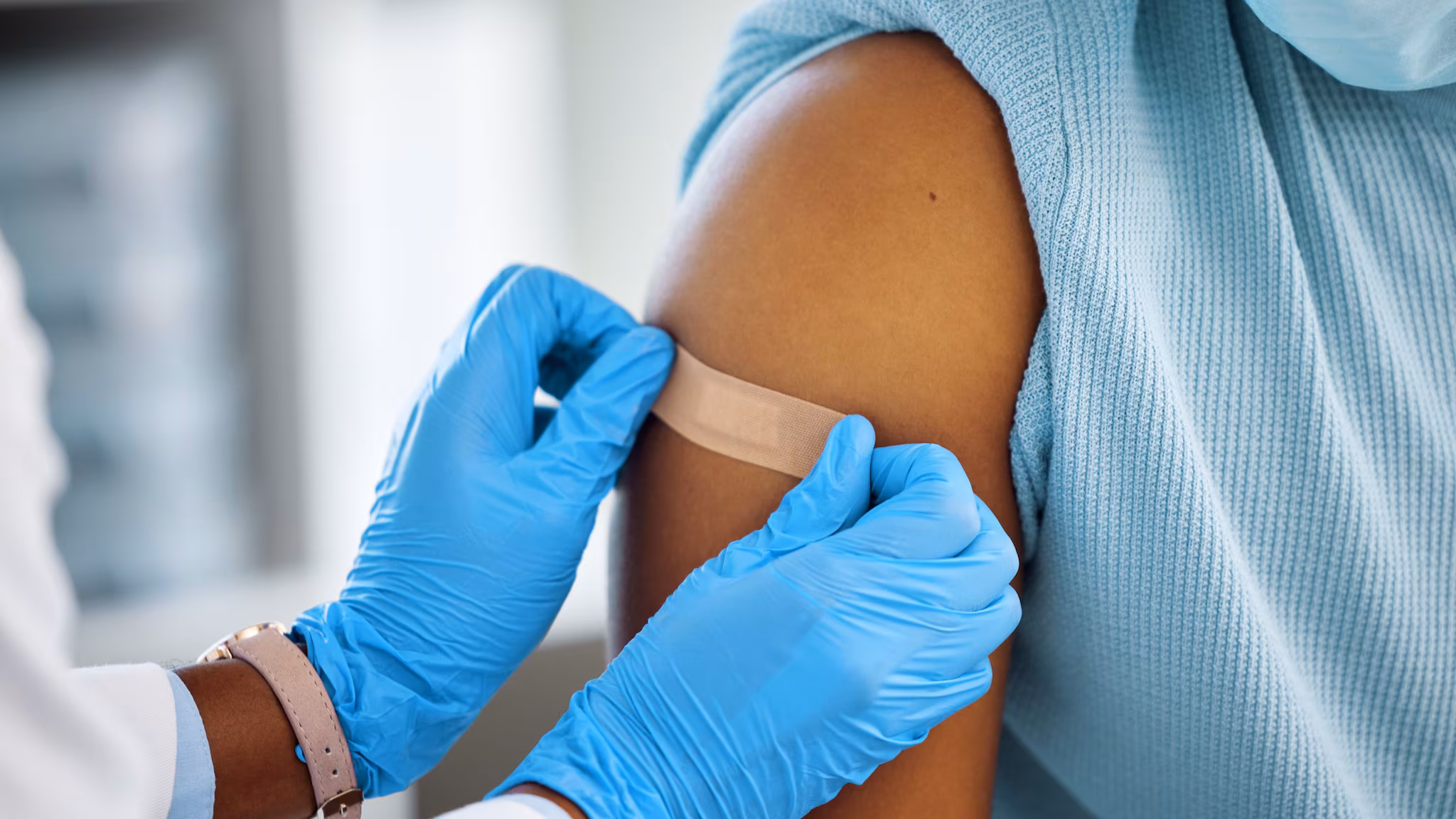 two hands placing a bandage on an arm
