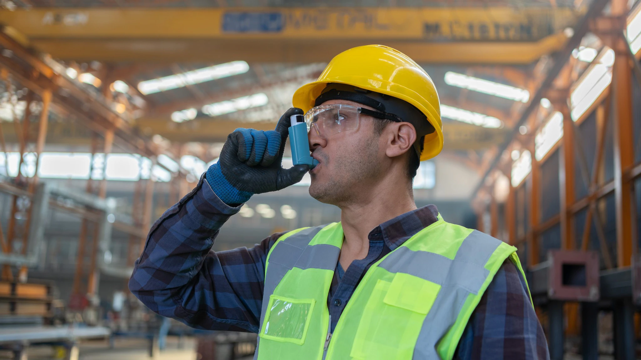 worker inhaler Man at work, wearing a hard hat and using an inhaler. Image by Getty Images.