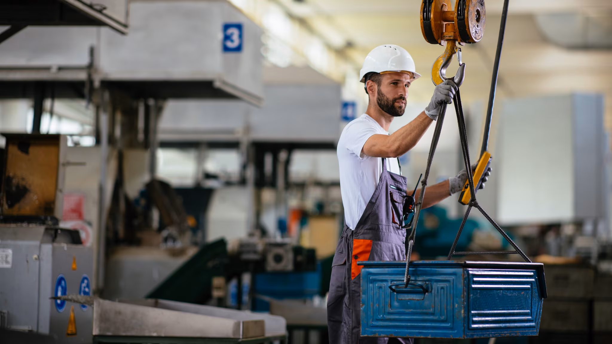 A man uses a crane to assist a lift in a manufacturing setting